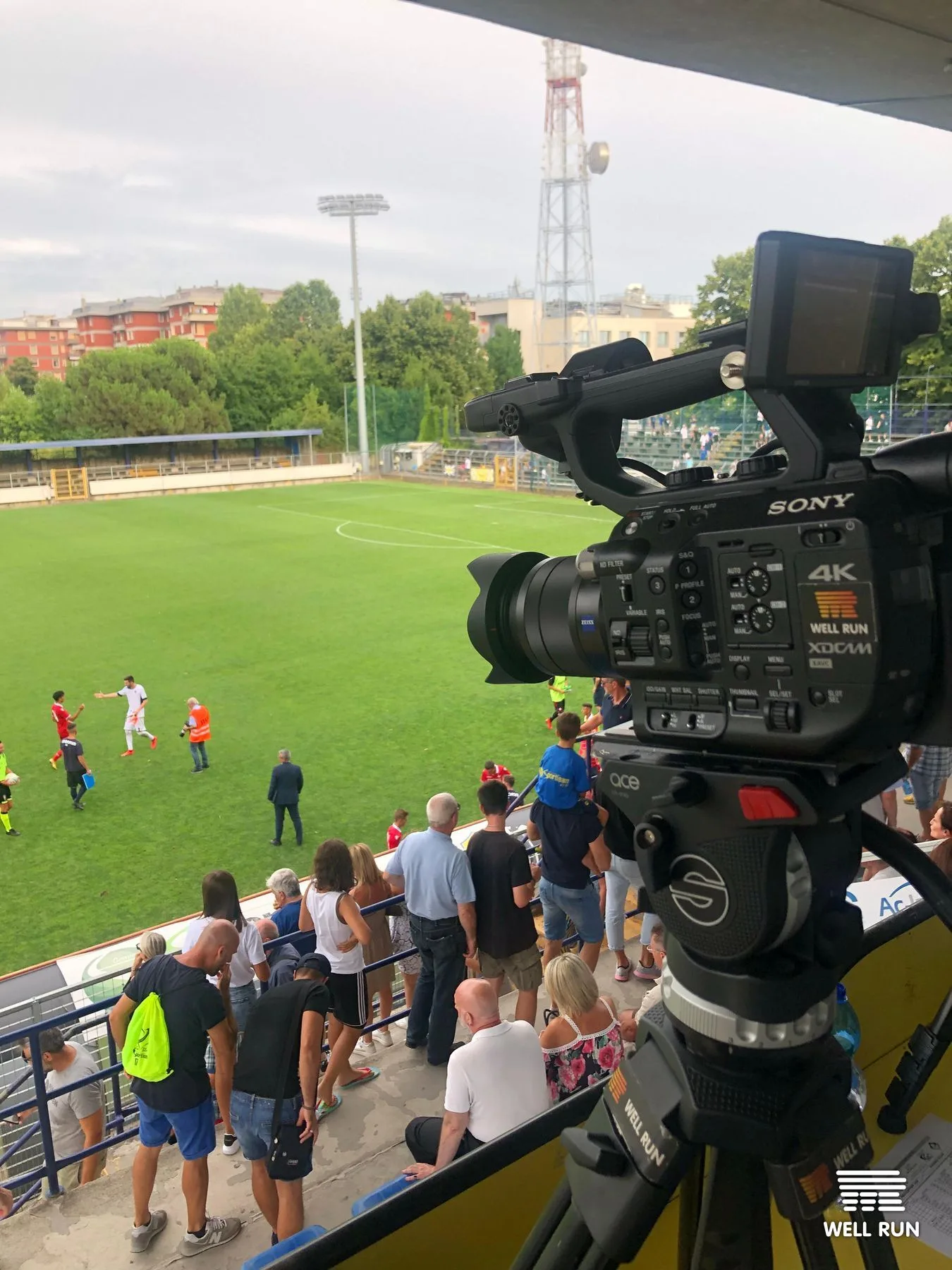 Sony 4K XDCAM camera on tripod overlooking football pitch with spectators at Crema stadium — frame 1