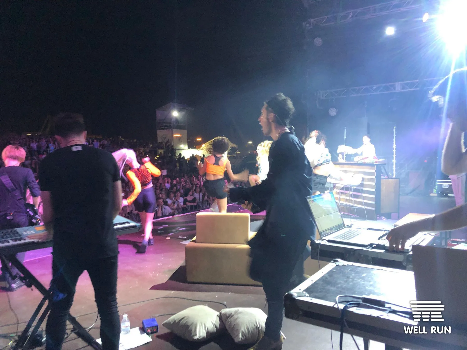 View from backstage at Dan Balan concert in Odessa showing performers, crew, laptops and keyboard rigs on lit stage