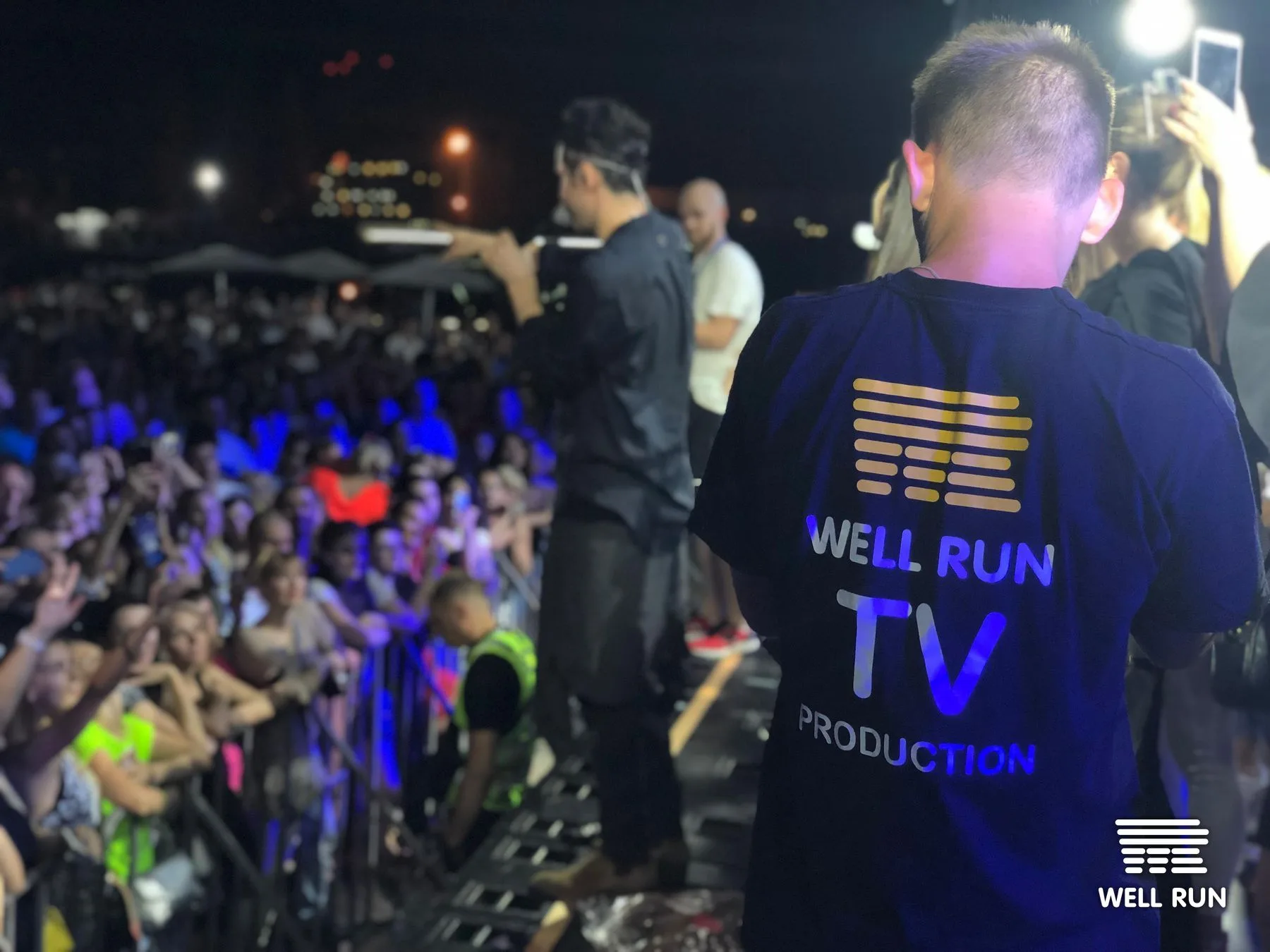 Well Run TV Production crew member in branded shirt watches Dan Balan perform on stage in Odessa