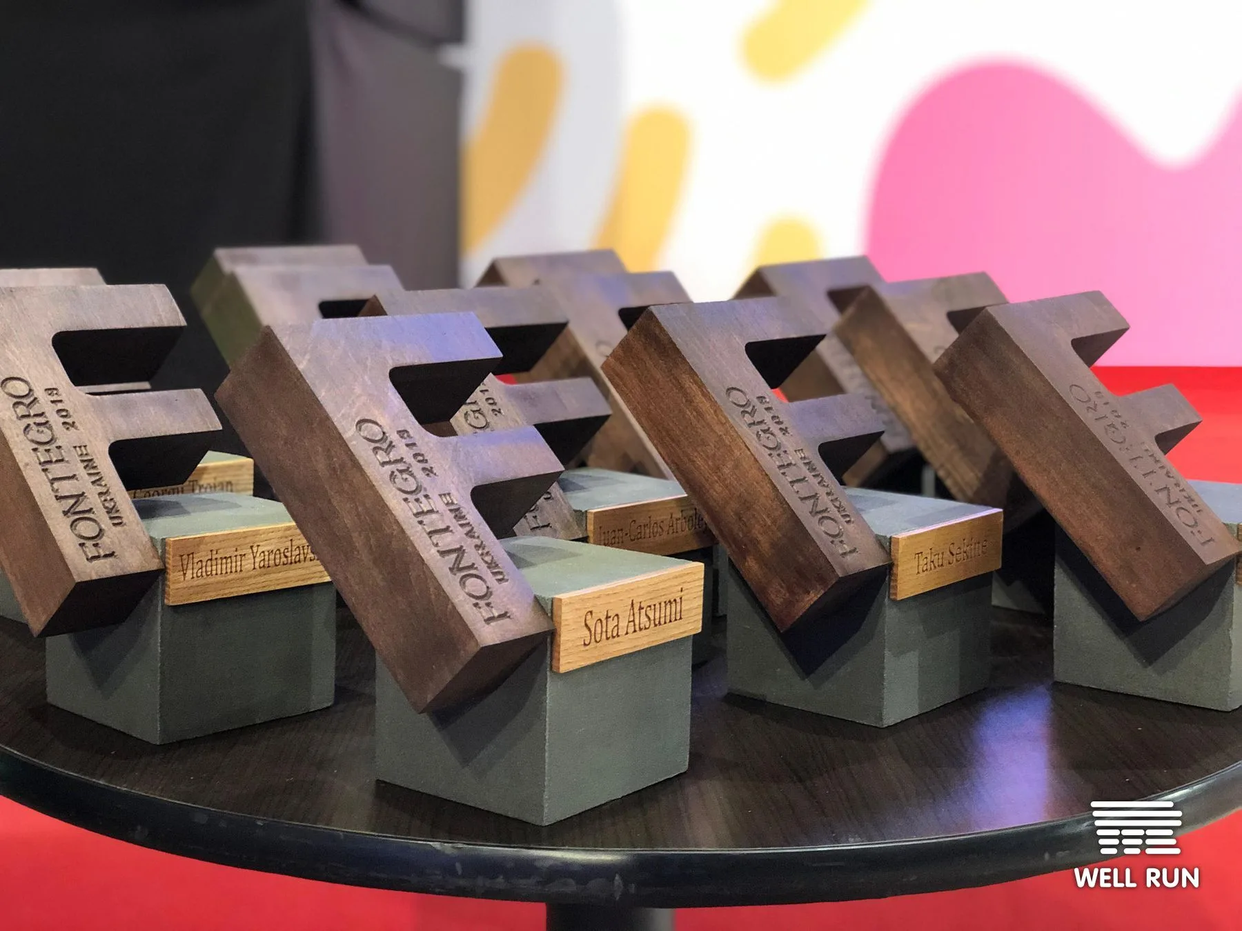 Ten engraved wooden Fontegro Ukraine 2019 award trophies on concrete bases, displayed on a round table