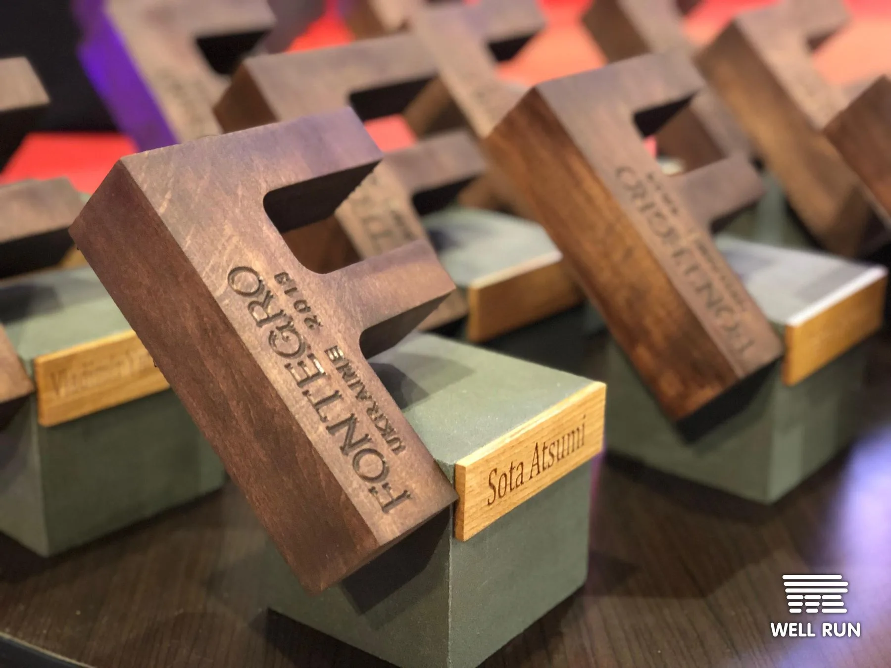 Row of wooden Fontegro Ukraine Chefs Congress 2019 trophies on concrete bases, foreground engraved Sota Atsumi