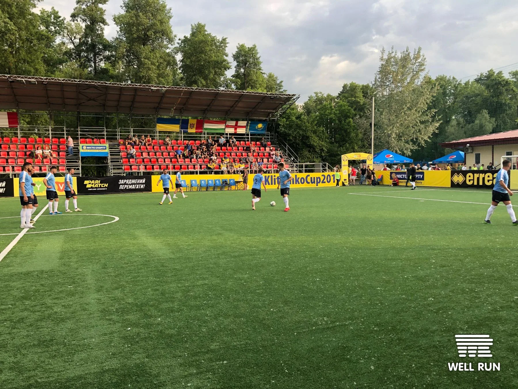 Players in light blue kits compete on artificial pitch at Klitschko Cup 2019, Hydropark Arena, Kyiv