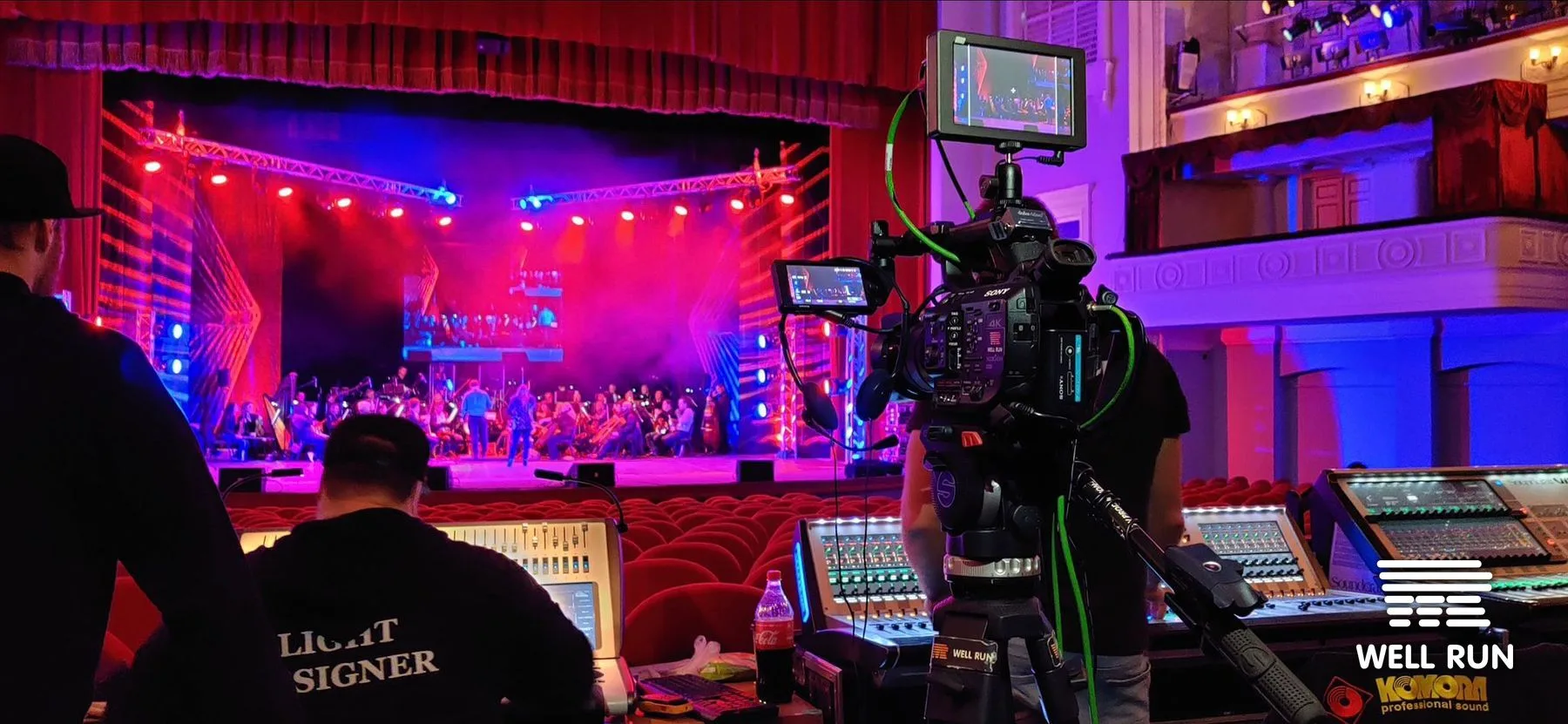 Sony camera on tripod filming lit stage with orchestra at October Palace, Kyiv, 2019 — frame 1