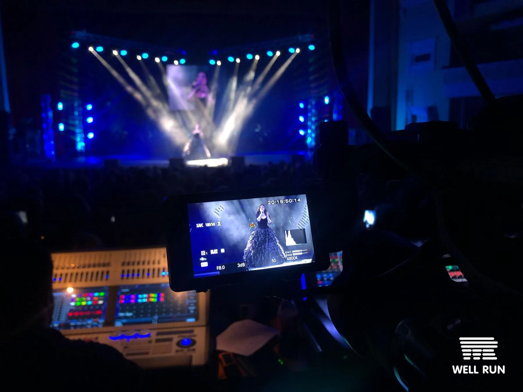 Camera viewfinder shows performer on stage at October Palace during live Musical Evening broadcast