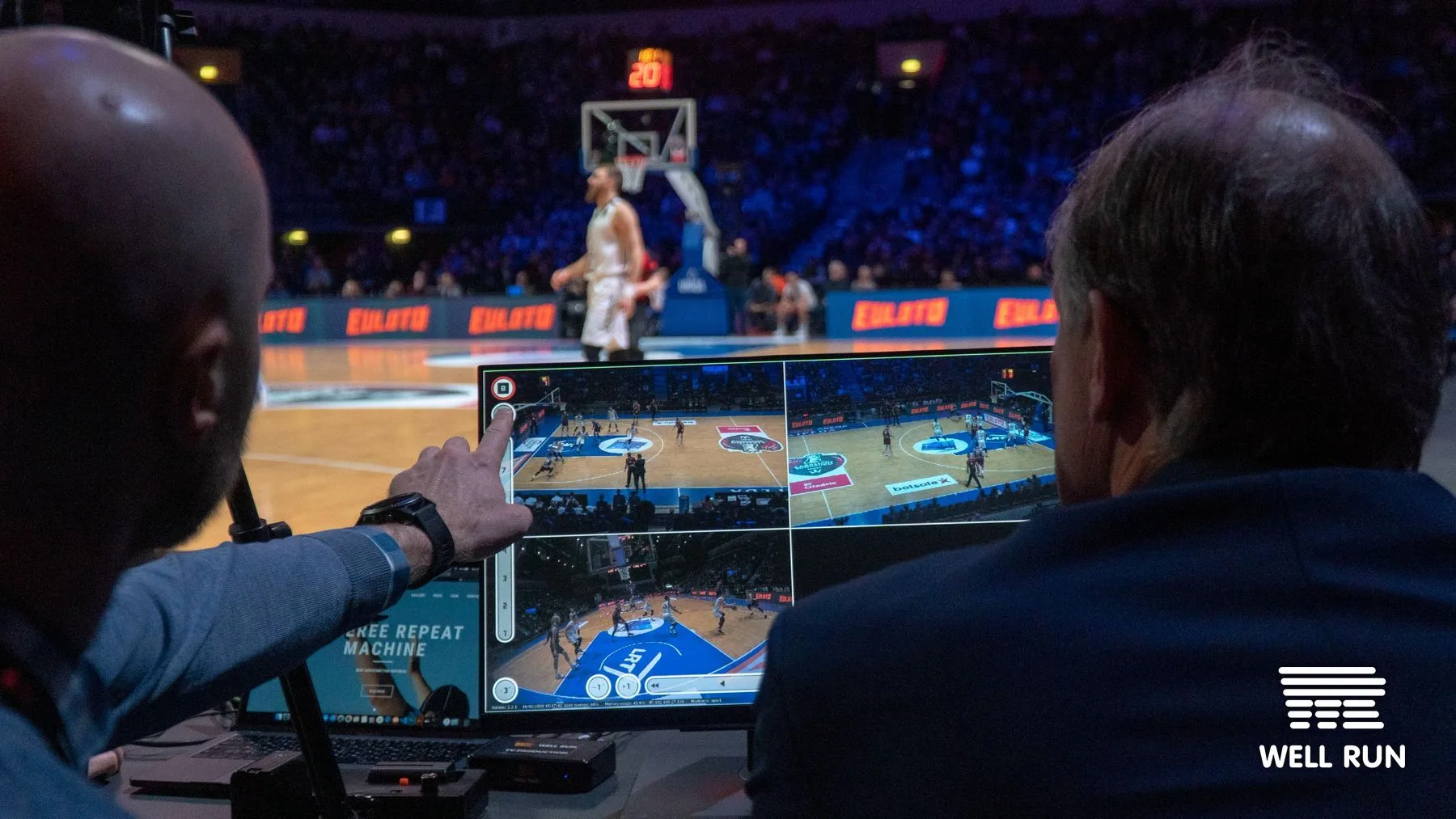 Two officials at courtside table review multi-camera RRM touchscreen during LKL basketball final at Švyturys Arena — frame 7