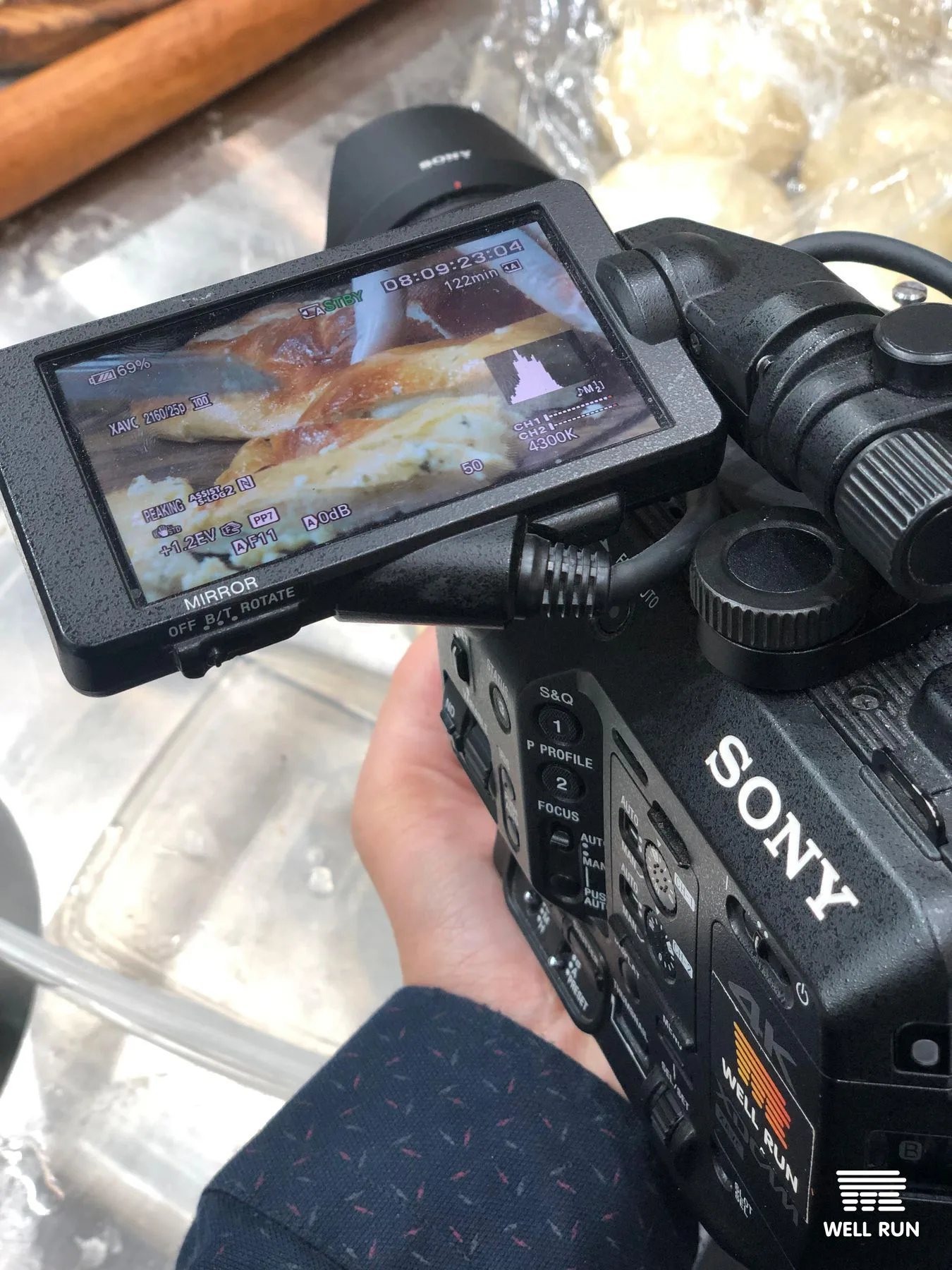 Kostiantyn Moseichenko holds Sony camera reviewing LCD screen showing pastry close-up at FoReCH expo