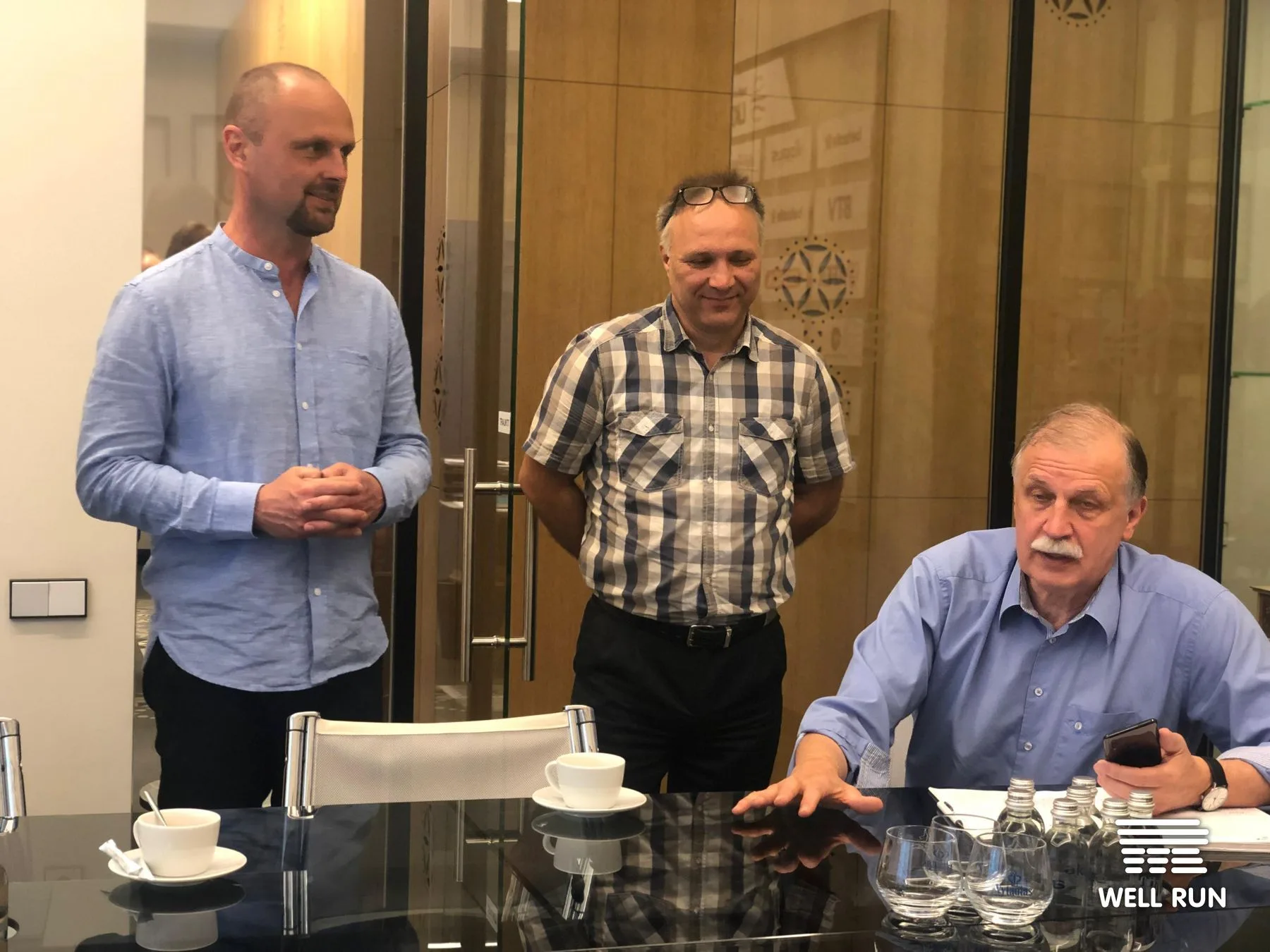 Three men in discussion at a conference table at LKL headquarters in Vilnius discussing RRM