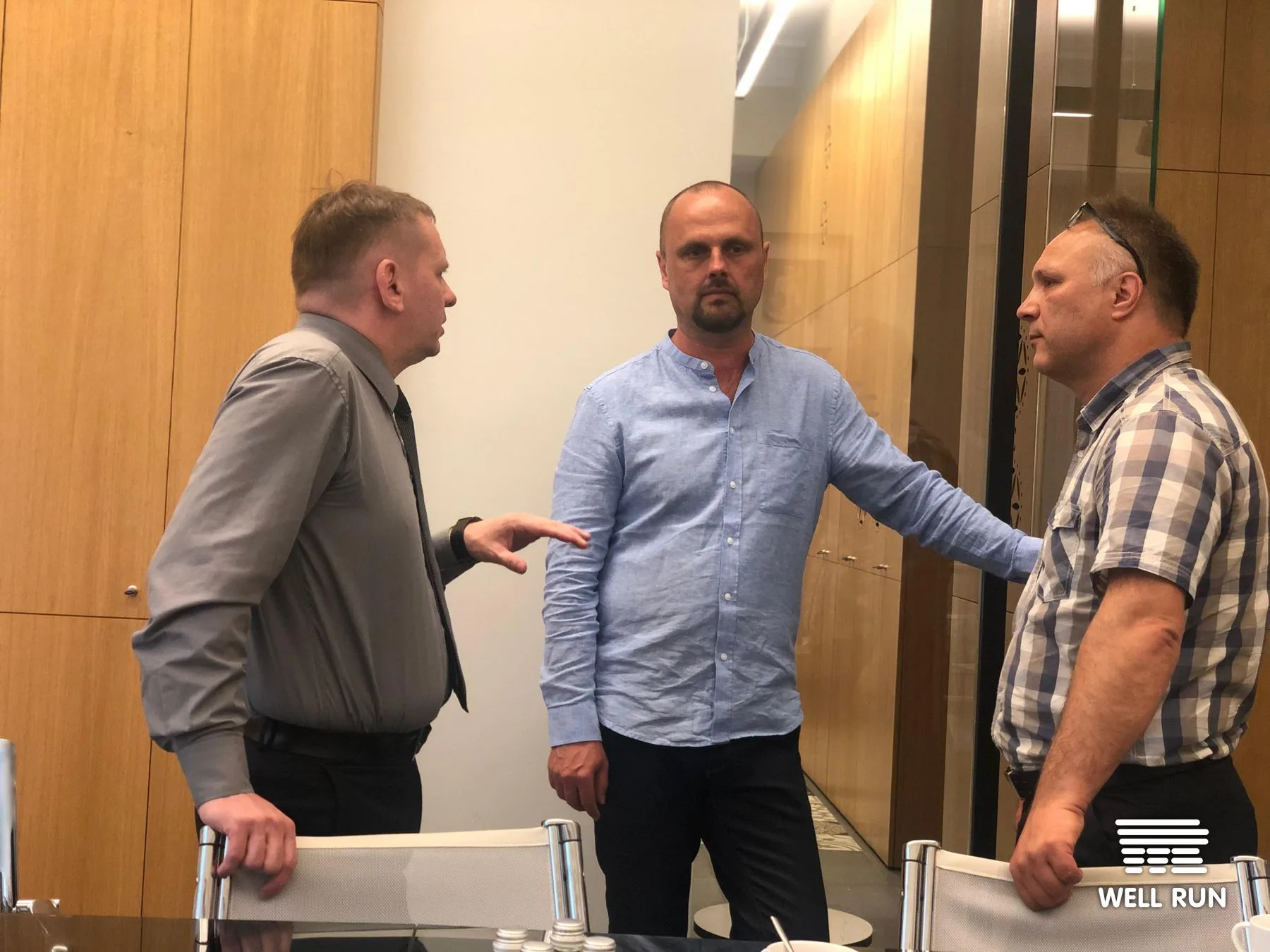 Three men in discussion at LKL headquarters reviewing RRM portable VAR system details, Vilnius