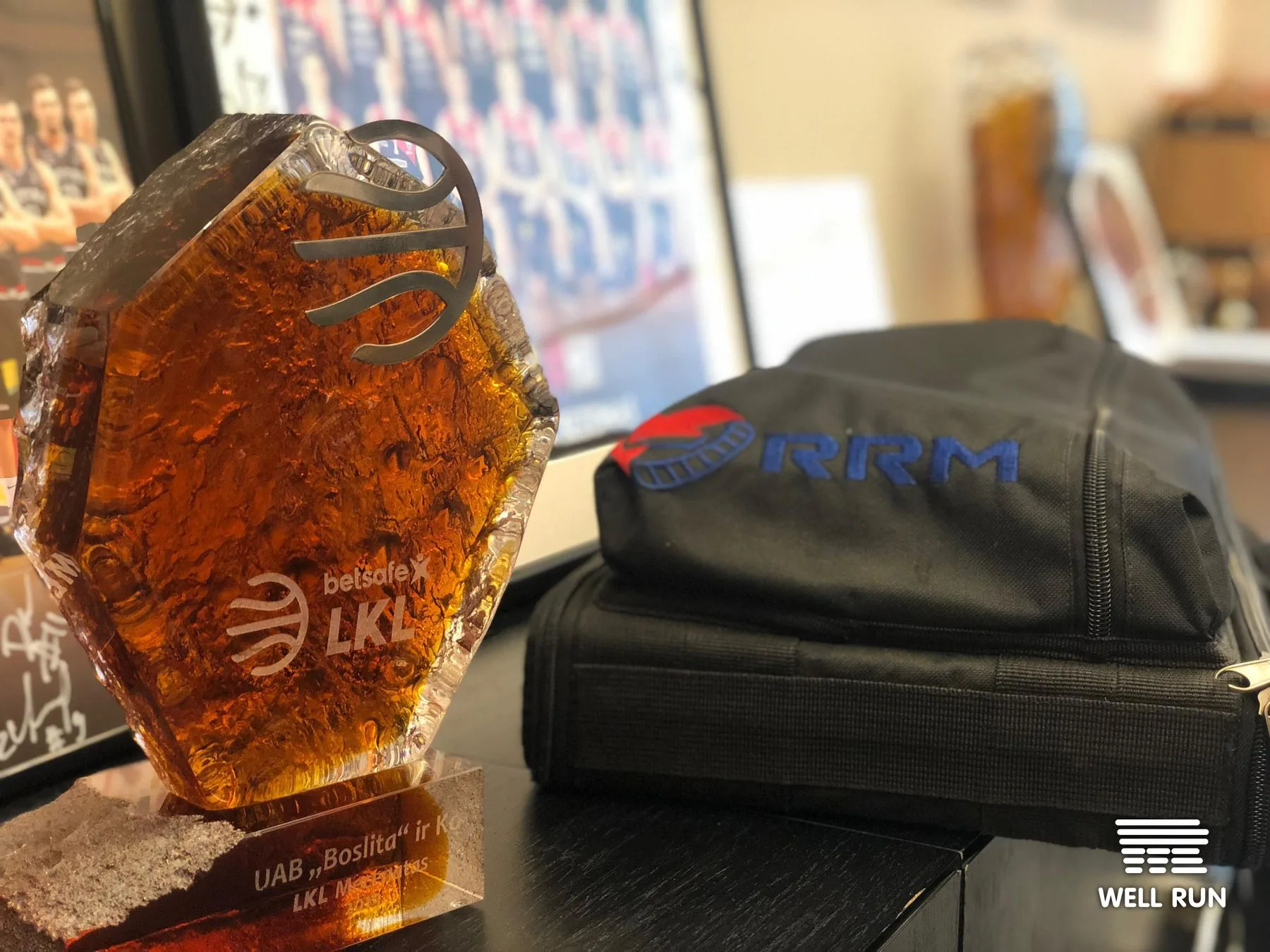 Amber LKL Betsafe trophy beside black RRM portable case on dark desk, Vilnius