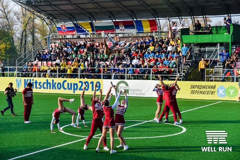 Cheerleaders toss teammate into air on green pitch at Hydropark Arena, Kyiv, crowd watching — frame 1