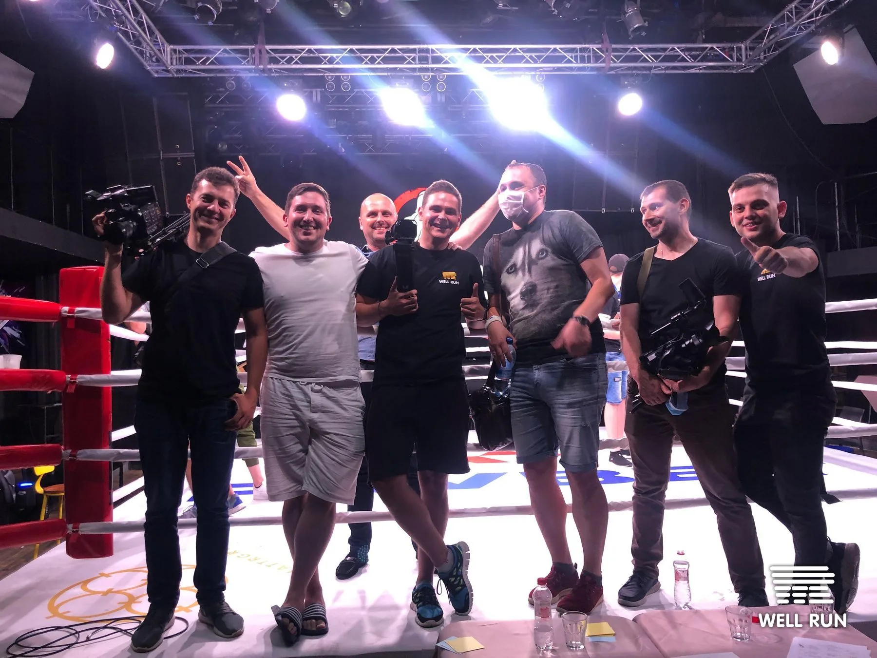 Seven-person Well Run production crew smiling ringside at Club Atlas boxing venue, Kyiv