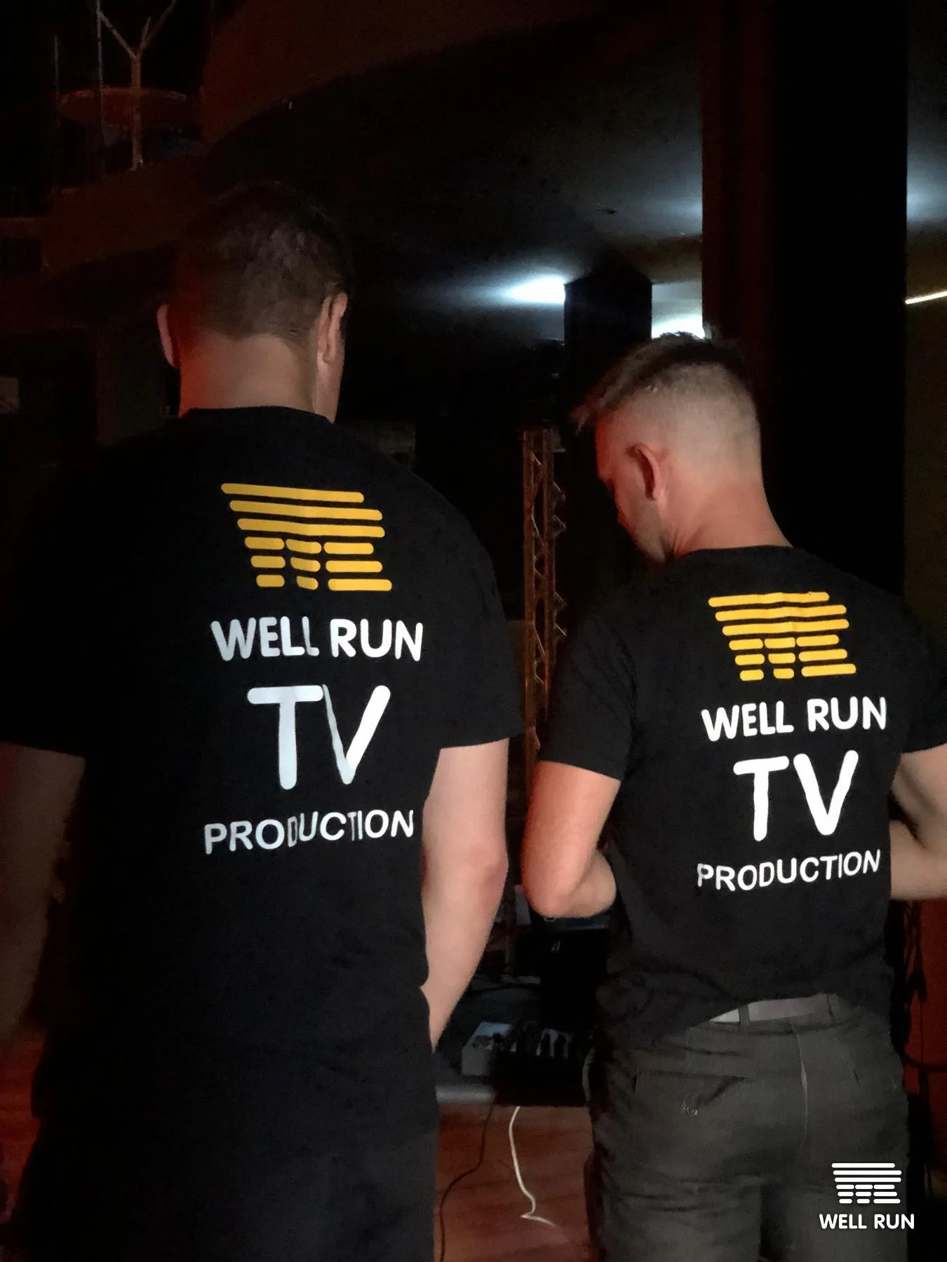 Two crew members in Well Run TV Production shirts seen from behind at Club Atlas Kyiv — frame 5